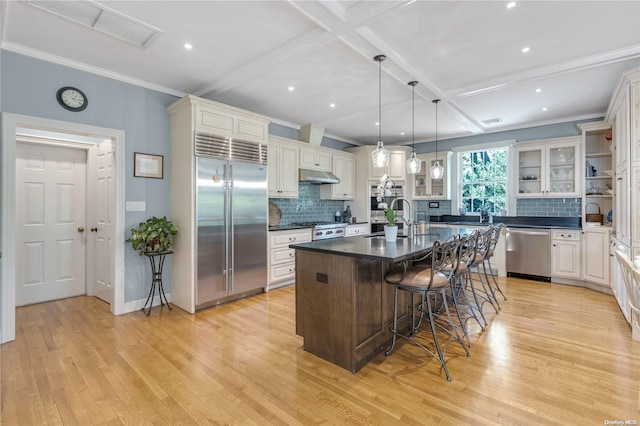 kitchen featuring a kitchen island with sink, a kitchen breakfast bar, hanging light fixtures, light hardwood / wood-style flooring, and stainless steel appliances