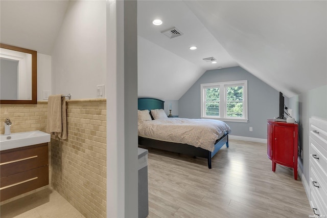 bedroom featuring light hardwood / wood-style floors, sink, and vaulted ceiling