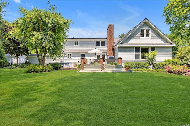 rear view of house featuring a wooden deck and a yard