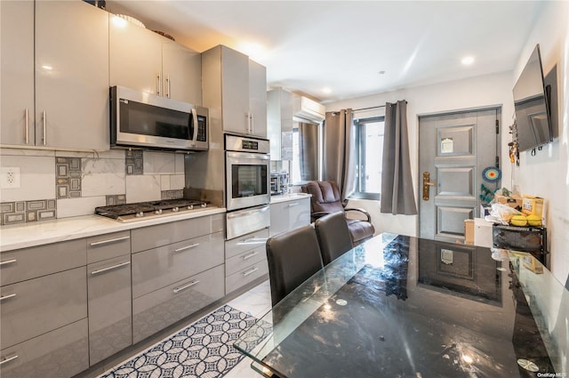 kitchen with stone counters, stainless steel appliances, tasteful backsplash, and gray cabinetry