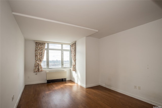 empty room featuring radiator and dark hardwood / wood-style floors