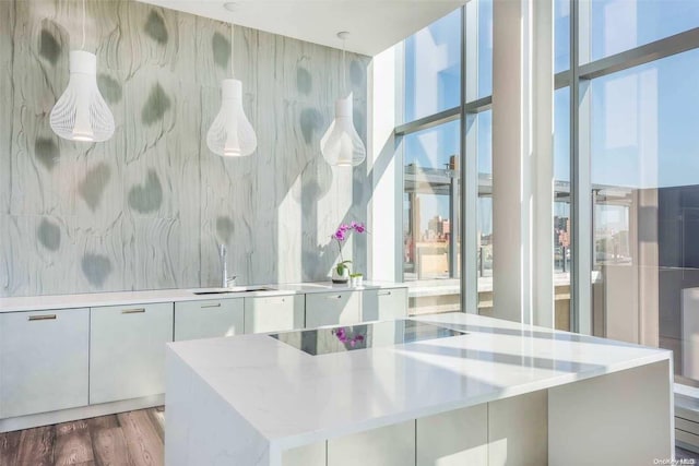 kitchen featuring sink, a kitchen island, light stone counters, white cabinets, and hardwood / wood-style flooring