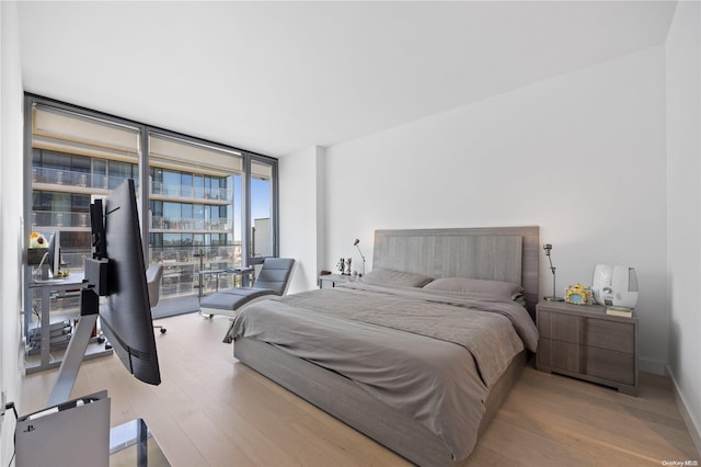 bedroom with expansive windows and light hardwood / wood-style floors