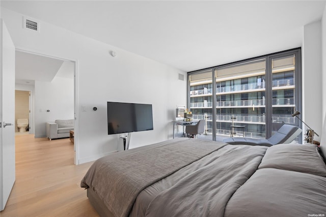 bedroom with floor to ceiling windows and light hardwood / wood-style flooring