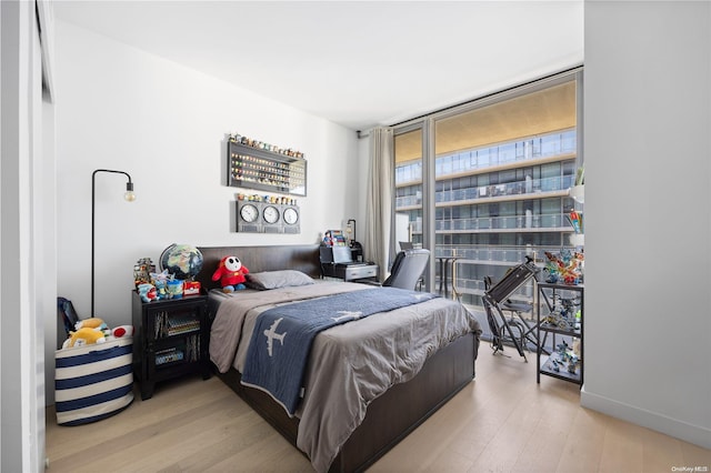 bedroom with light hardwood / wood-style floors and expansive windows