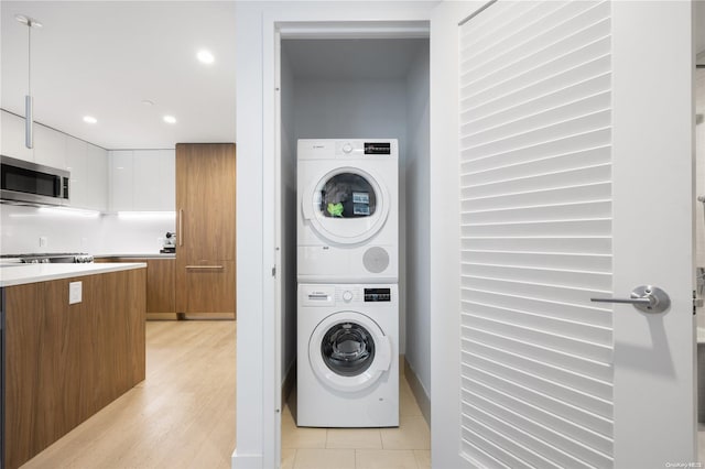 laundry room featuring light hardwood / wood-style floors and stacked washing maching and dryer