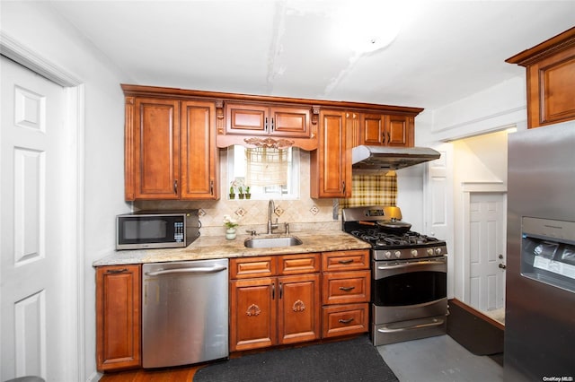 kitchen featuring decorative backsplash, sink, light stone counters, and appliances with stainless steel finishes