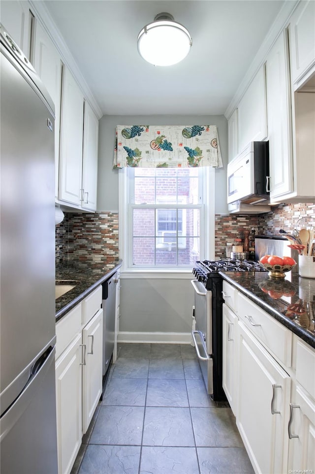 kitchen with dark stone counters, tile patterned floors, appliances with stainless steel finishes, tasteful backsplash, and white cabinetry