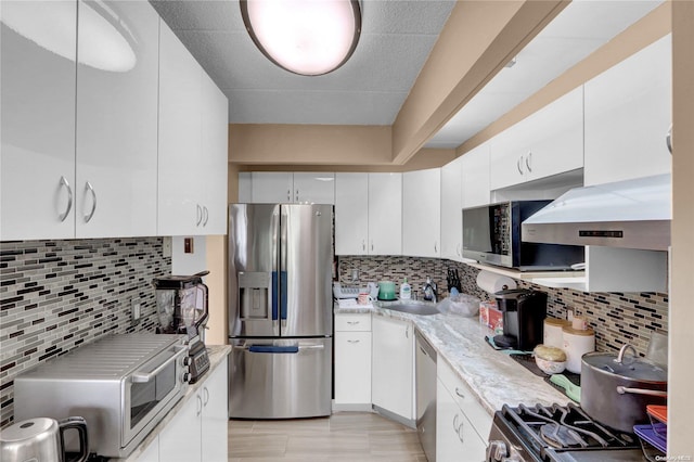 kitchen featuring sink, tasteful backsplash, light stone counters, white cabinetry, and stainless steel appliances