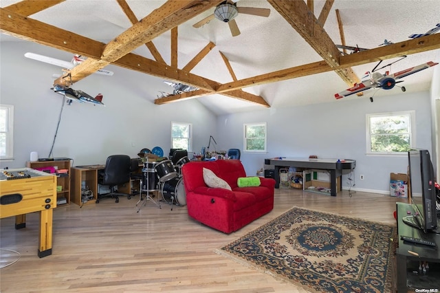 rec room with vaulted ceiling with beams, ceiling fan, a healthy amount of sunlight, and light wood-type flooring