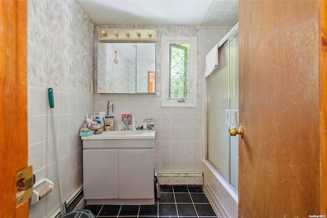 bathroom with tile patterned floors, vanity, bath / shower combo with glass door, and tile walls