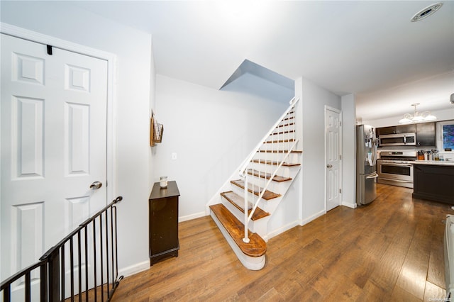 stairway with an inviting chandelier and hardwood / wood-style flooring