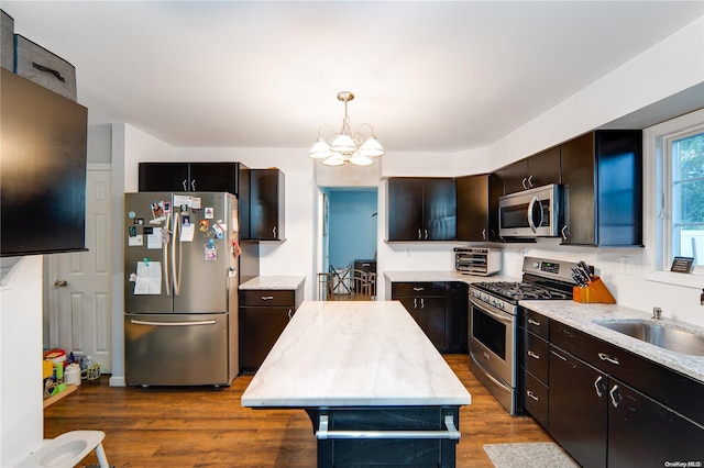 kitchen with stainless steel appliances, wood-type flooring, decorative light fixtures, a chandelier, and a kitchen island