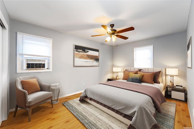 bedroom with multiple windows, ceiling fan, hardwood / wood-style floors, and cooling unit