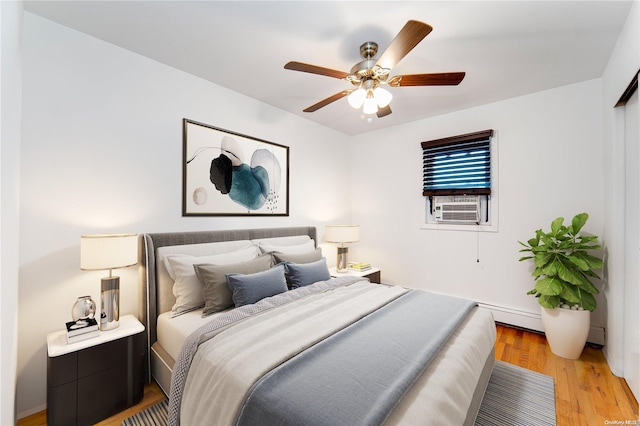 bedroom with ceiling fan, cooling unit, light hardwood / wood-style floors, and a baseboard heating unit