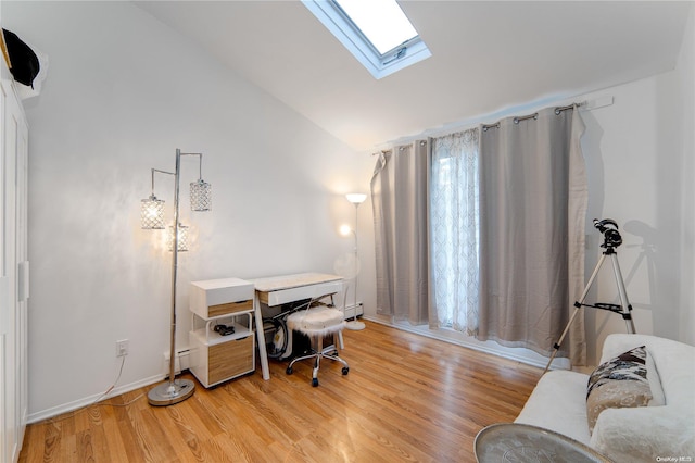 home office featuring hardwood / wood-style flooring, lofted ceiling with skylight, and a baseboard heating unit