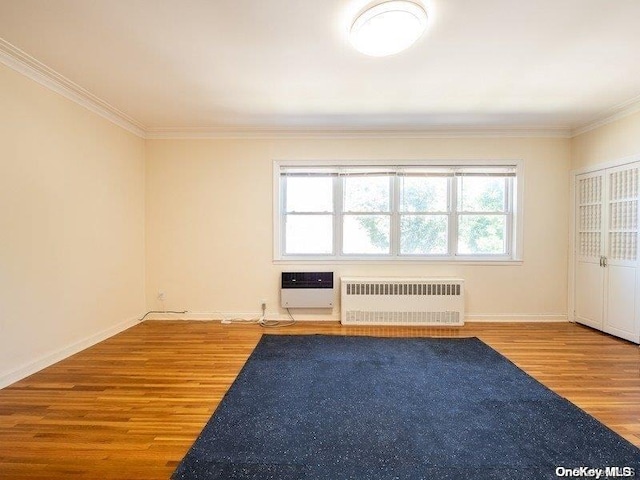 unfurnished room with heating unit, crown molding, radiator heating unit, and hardwood / wood-style floors