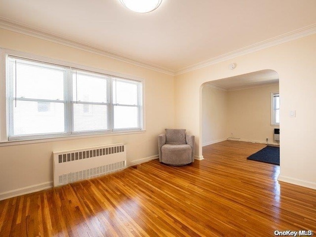 unfurnished room with hardwood / wood-style flooring, crown molding, and radiator