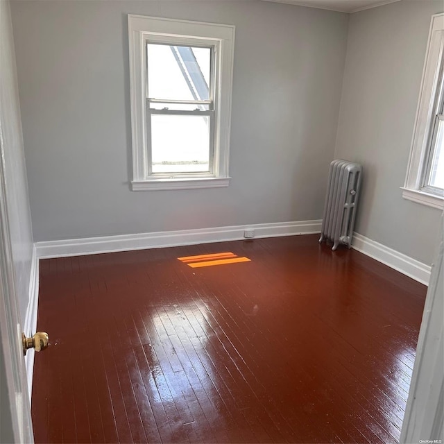 spare room featuring plenty of natural light, dark hardwood / wood-style floors, and radiator heating unit