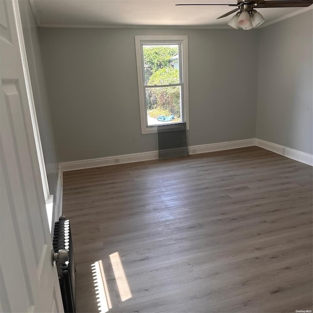 spare room with ceiling fan, radiator heating unit, wood-type flooring, and ornamental molding