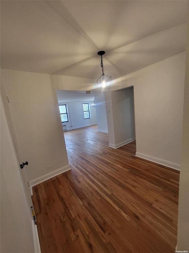 spare room featuring dark hardwood / wood-style floors and an inviting chandelier