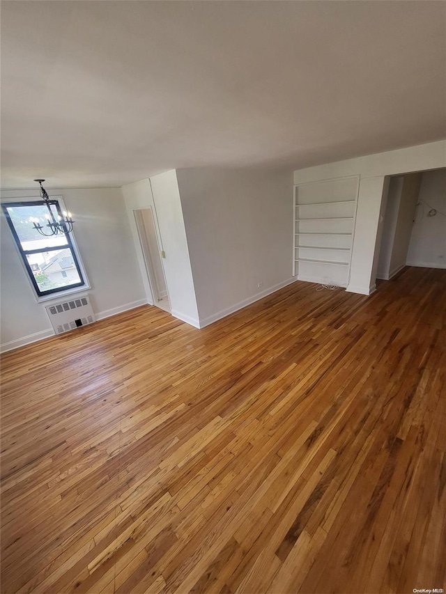 unfurnished living room with a chandelier and wood-type flooring