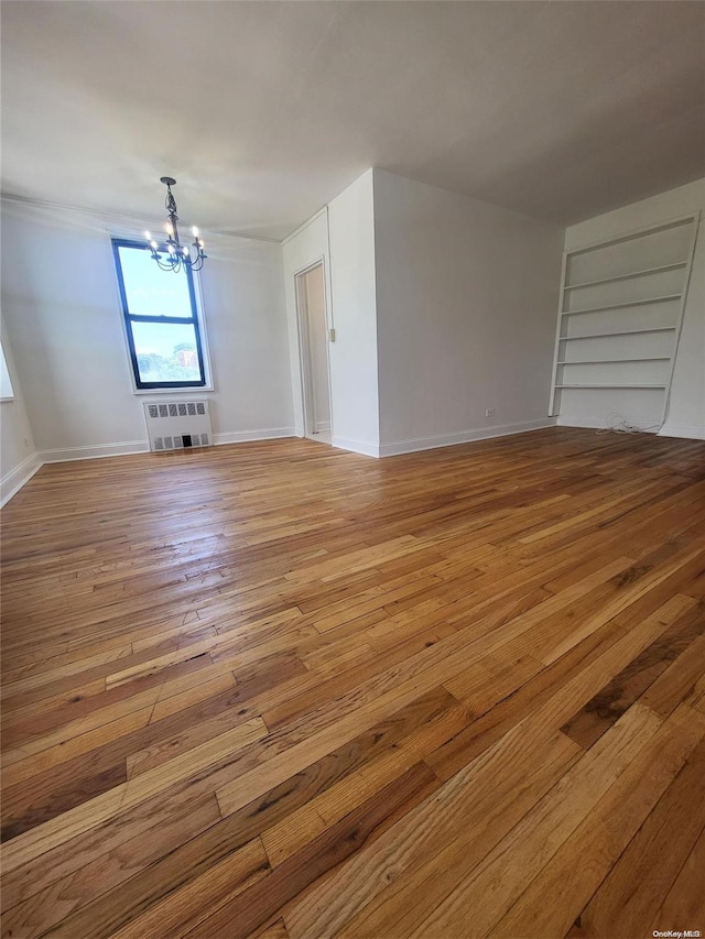 interior space with heating unit, an inviting chandelier, and light hardwood / wood-style flooring