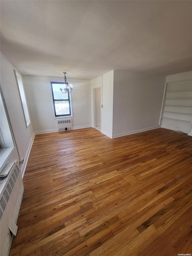 unfurnished living room featuring wood-type flooring and an inviting chandelier