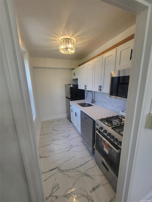 kitchen featuring white cabinets, appliances with stainless steel finishes, decorative backsplash, and sink