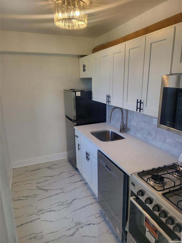 kitchen with sink, decorative backsplash, a notable chandelier, white cabinetry, and stainless steel appliances