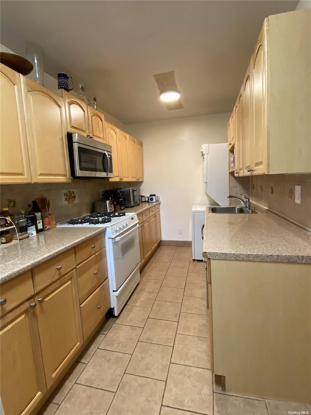 kitchen with tasteful backsplash, white range with gas cooktop, sink, light brown cabinets, and light tile patterned flooring