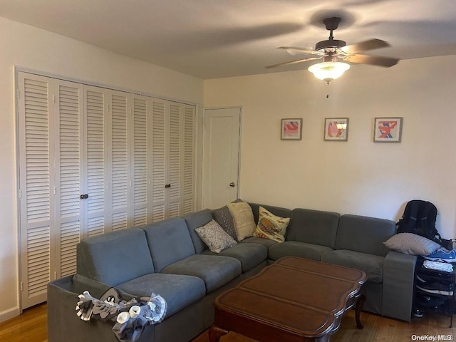 living room with ceiling fan and dark wood-type flooring