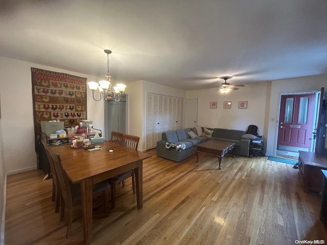 dining space featuring ceiling fan with notable chandelier and wood-type flooring