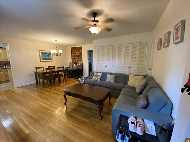 living room featuring ceiling fan with notable chandelier and light wood-type flooring