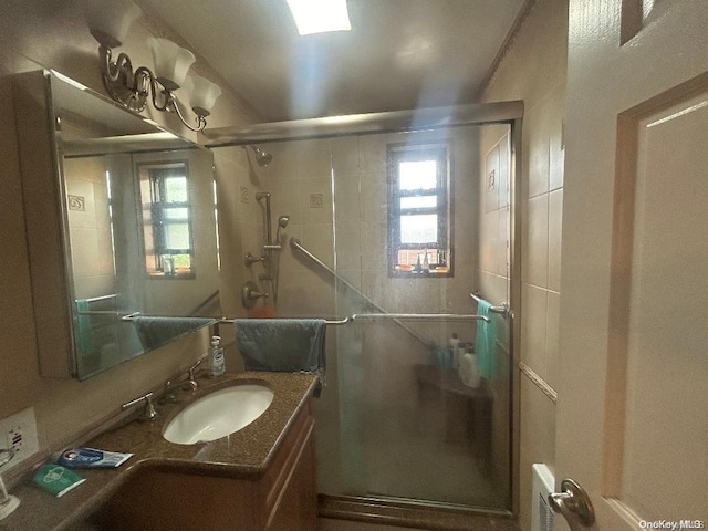 bathroom featuring a shower with door and vanity