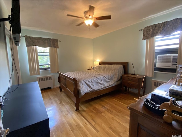 bedroom featuring radiator, ceiling fan, light hardwood / wood-style flooring, and cooling unit