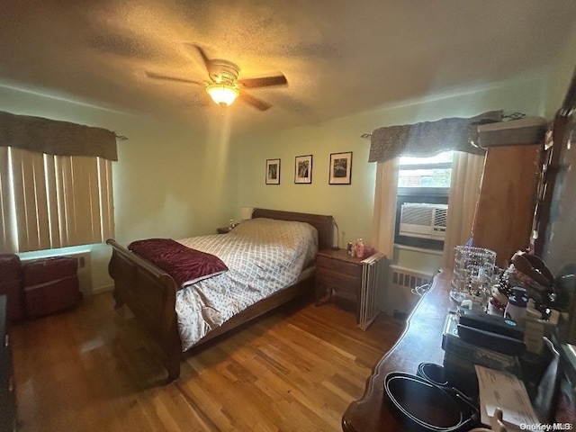 bedroom featuring radiator heating unit, a textured ceiling, ceiling fan, and hardwood / wood-style floors