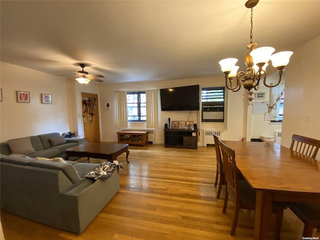 living room featuring ceiling fan with notable chandelier, light hardwood / wood-style floors, and radiator