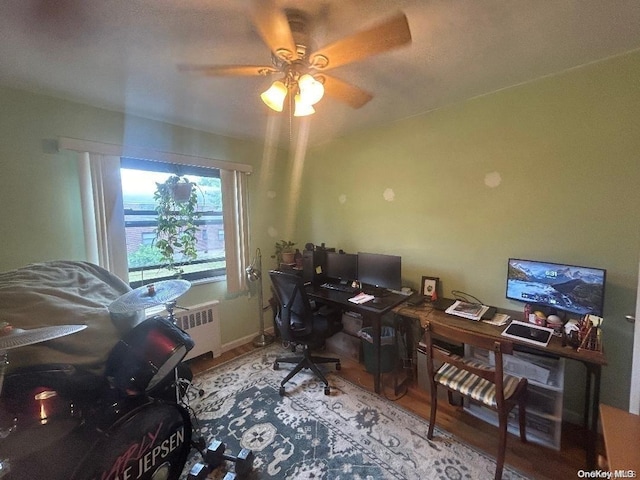 office featuring wood-type flooring, radiator, and ceiling fan