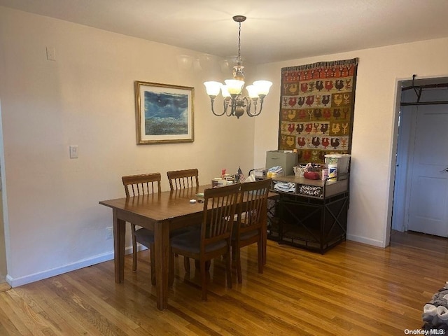 dining space with hardwood / wood-style floors, a barn door, and an inviting chandelier