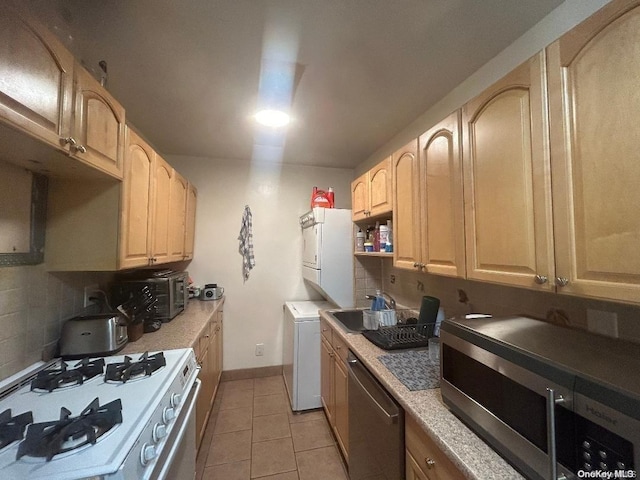 kitchen with tasteful backsplash, sink, stainless steel appliances, and washer / dryer