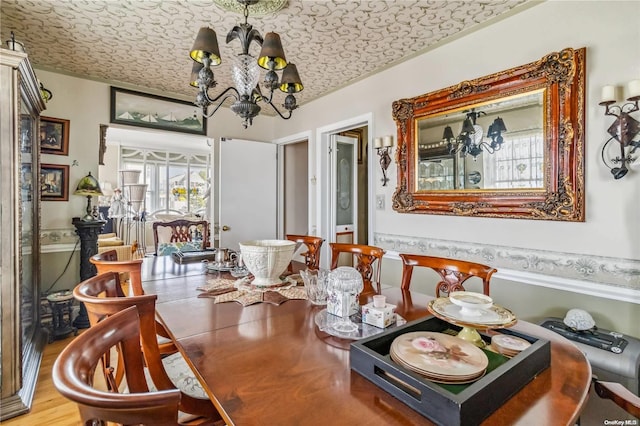 dining room featuring wood-type flooring, a notable chandelier, and a textured ceiling