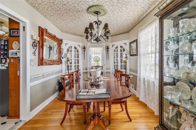 dining space with wood-type flooring, a notable chandelier, and a textured ceiling