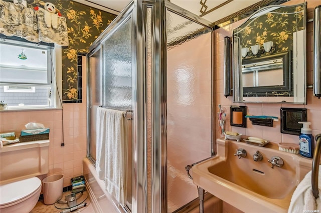 full bathroom with sink, tile walls, toilet, and combined bath / shower with glass door