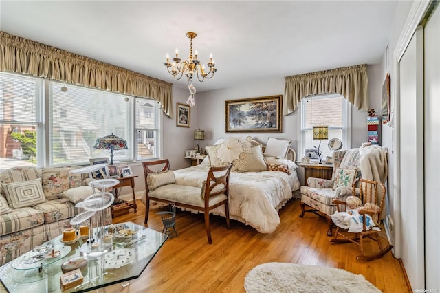 bedroom with light wood-type flooring, a closet, a chandelier, and multiple windows