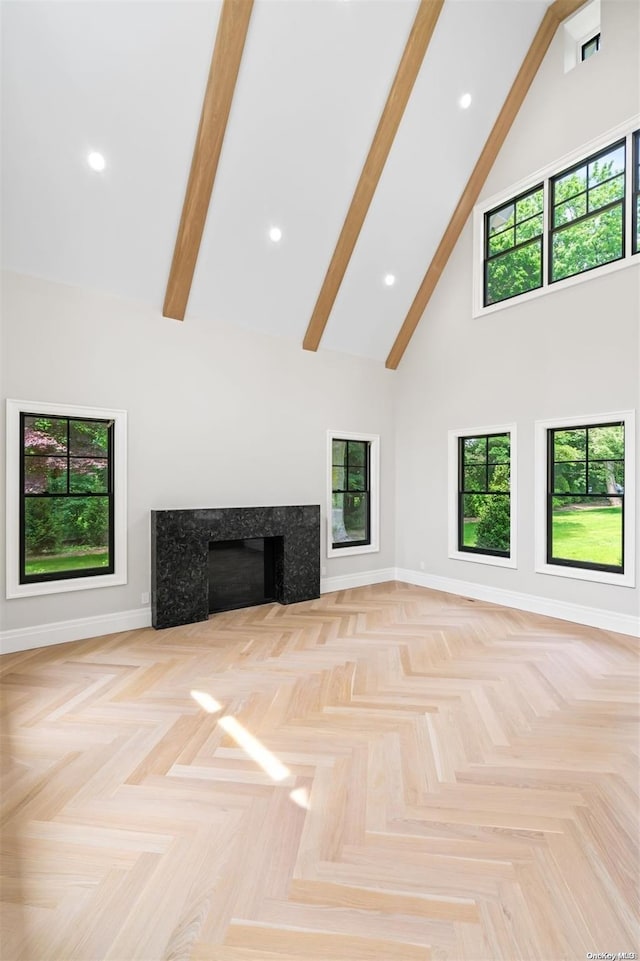 unfurnished living room with a high end fireplace, light parquet floors, high vaulted ceiling, and beamed ceiling