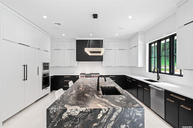 kitchen with appliances with stainless steel finishes, white cabinetry, a large island with sink, and sink