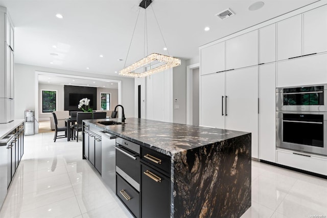 kitchen featuring dark stone counters, stainless steel double oven, a spacious island, pendant lighting, and white cabinets