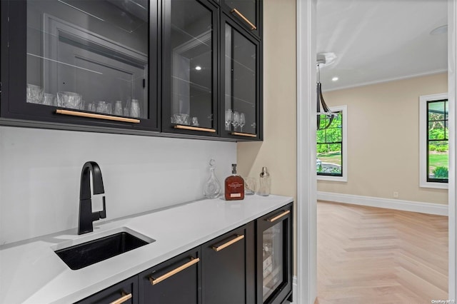 bar featuring a wealth of natural light, sink, beverage cooler, crown molding, and light parquet floors