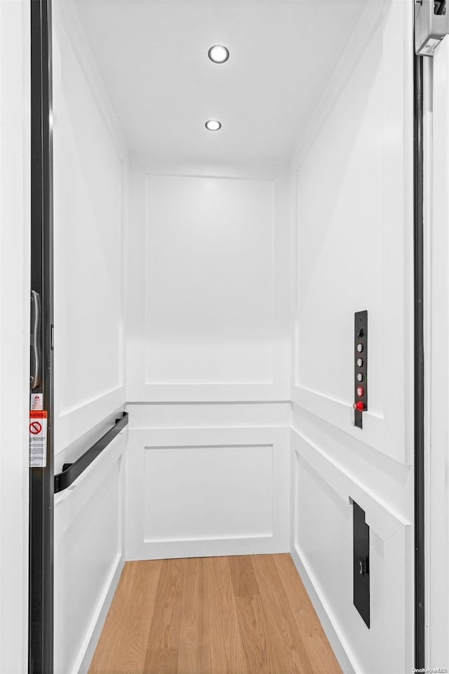 interior details with elevator, hardwood / wood-style floors, and ornamental molding